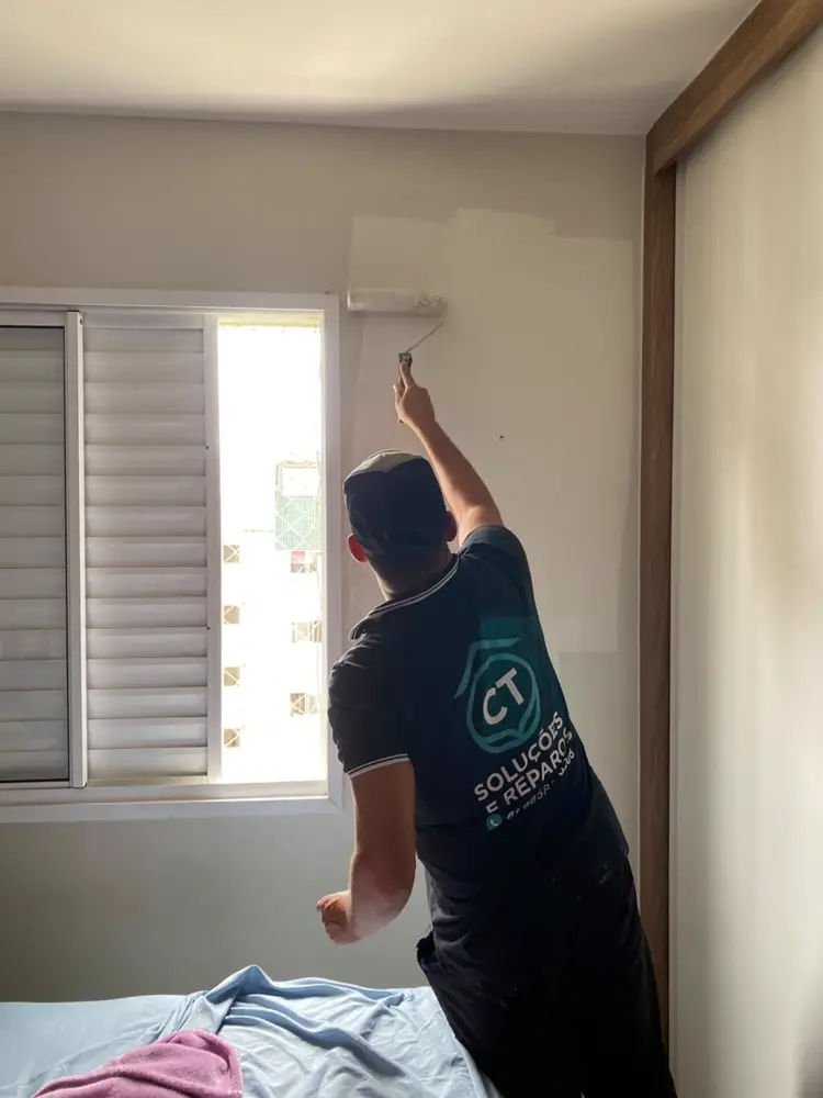 Pintor uniformizado da CT Soluções pintando parede de quarto em Brasília