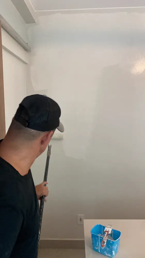 Aplicação de tinta com rolo em parede de apartamento no DF