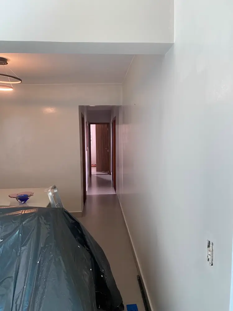 Sala e corredor recém-pintados com móveis protegidos por lona